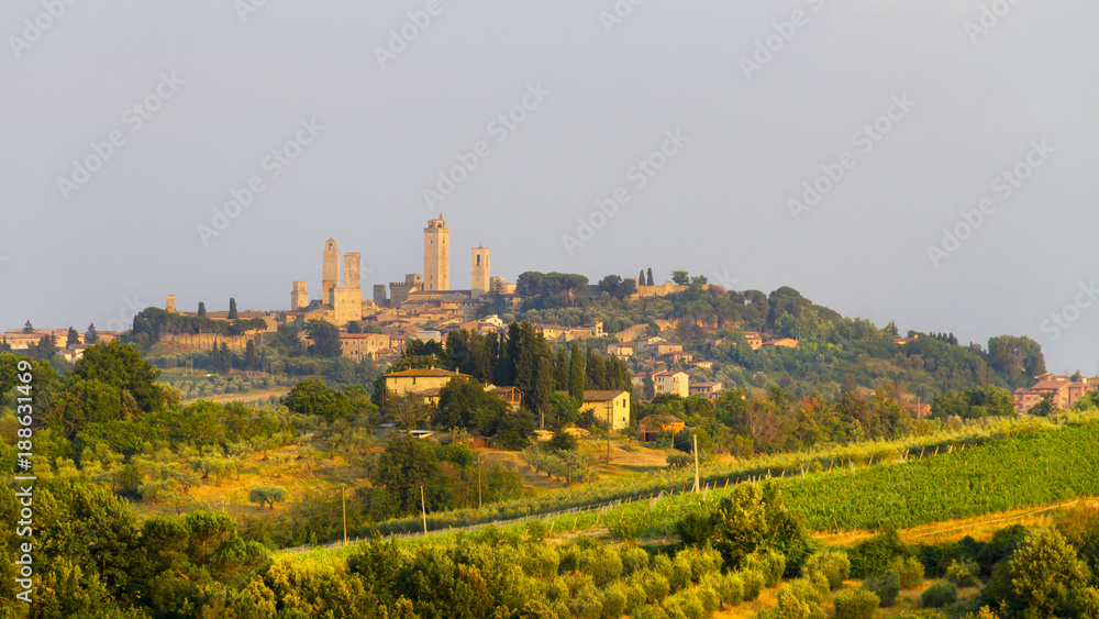 Idyllic and scenic landscape - vineyard and old town San Gimignano with fourteen towers on the top of the hill, Tuscany, Italy; tourism, travel, vacation; background.