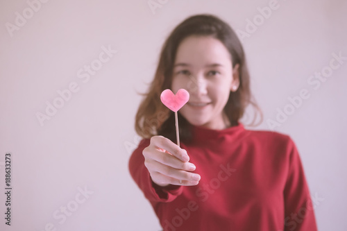 Portrait of Happy asian woman dressed in red sweater holding pink heart candy.