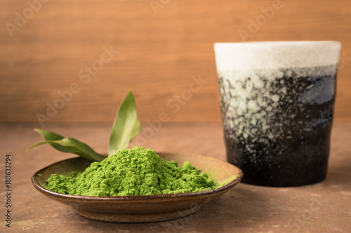 Close up of green tea powder in dish with ceramic cup on the table.
