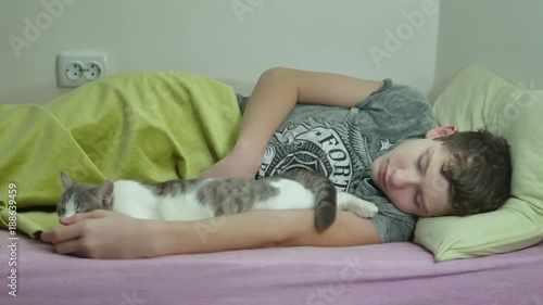 Teenage boy asleep in bed. man tired shaggy teenage indoors boy sleeping and pet cat photo