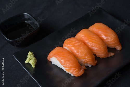 Salmon sushi on black plate with soy sauce