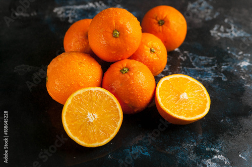 Ripe juicy oranges on a dark background. Water drops. Soft focus. Close up. Low key lighting
