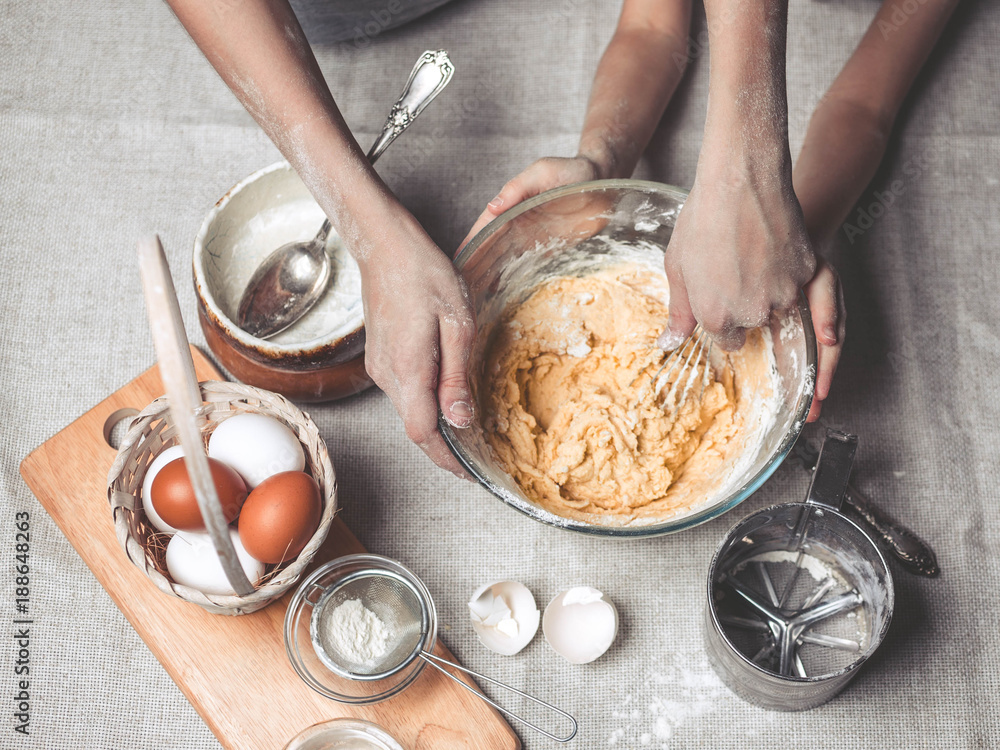 Fototapeta premium Mothers and children's hands cook dough for home-made cookies. We cook in kitchen together with children. Happy family