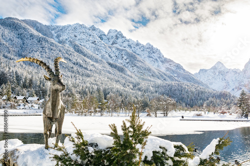 Sunny day at lake Jasna in Kranjska Gora guarded by statue of a Capricorn