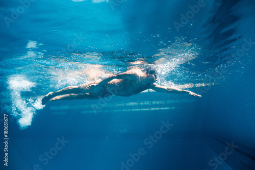 underwater picture of young swimmer in goggles exercising in swimming pool