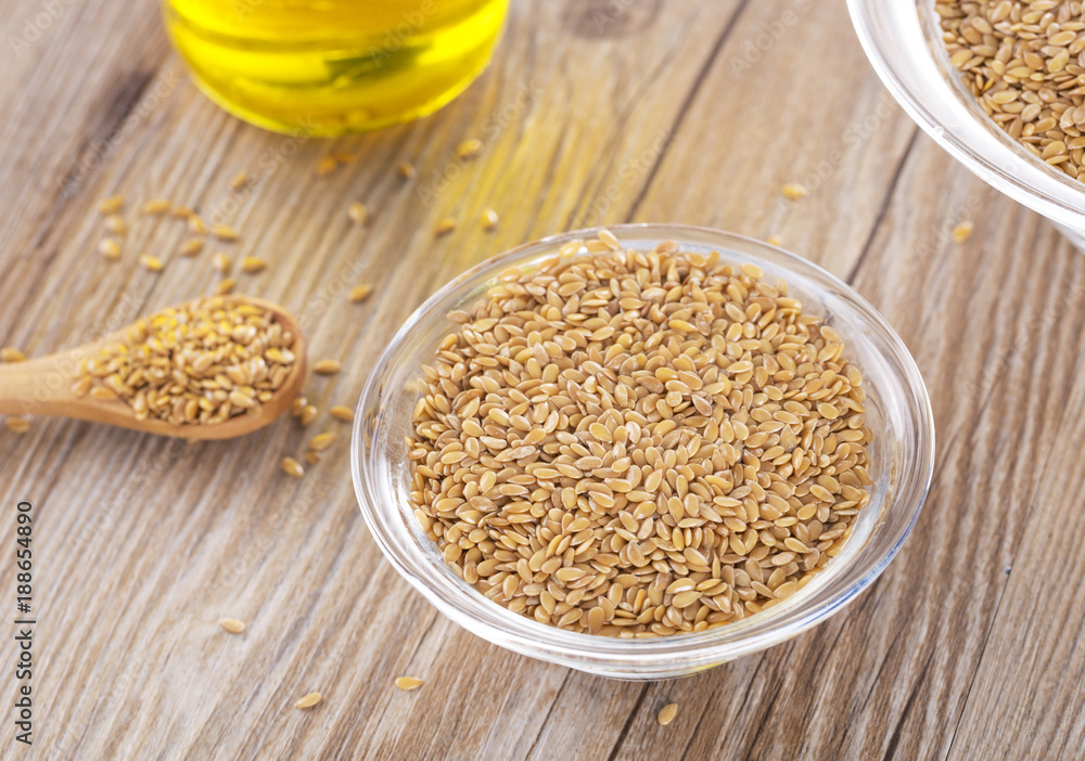 Bottle of flax seed oil ans seeds on wooden table.