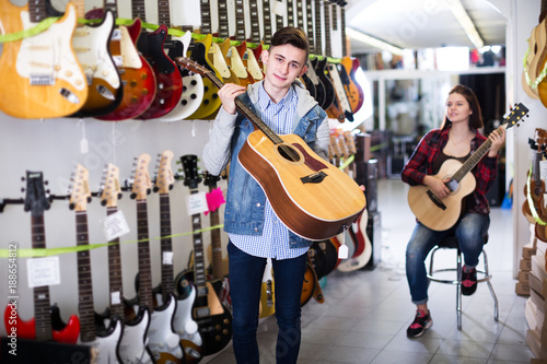 Teenagers examining guitars in shop