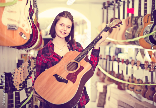 Nice teen girl examining various acoustic guitars