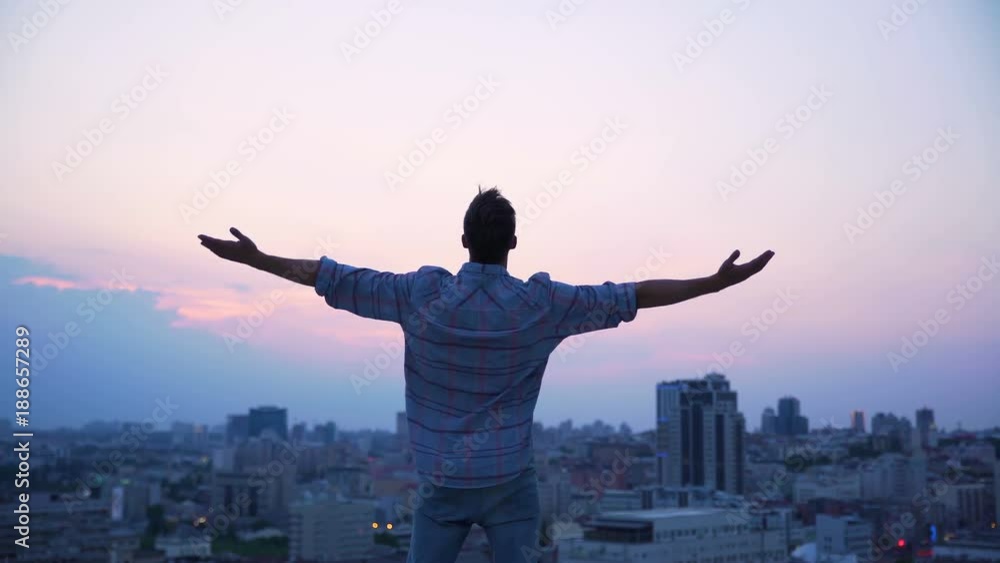 Man throwing his hands on roof edge, enjoying freedom, believe in future success Man throwing his hands on roof edge, enjoying freedom, believe in future success