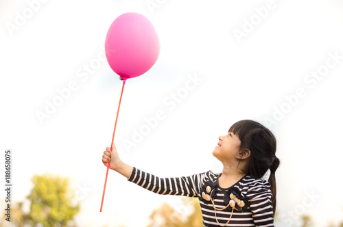 Happy little asian girl holding pink balloon in hand selective focus.