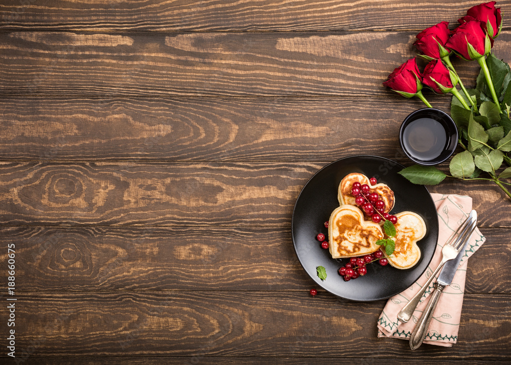 Valentine's day background with delicious pancakes in form of heart, green tea, candles and roses. Valentines day concept greeting card. Top view. Copy space.