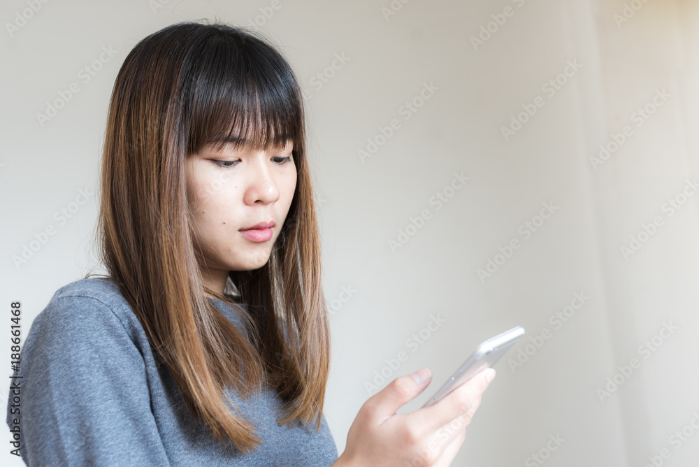 Asian woman using smart phone with wall Asian woman using smart phone with wall