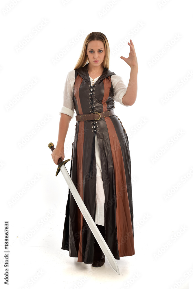 full length portrait of girl wearing brown fantasy costume, holding a sword. standing pose on white studio background. full length portrait of girl wearing brown fantasy costume, holding a sword. standing pose on white studio background.