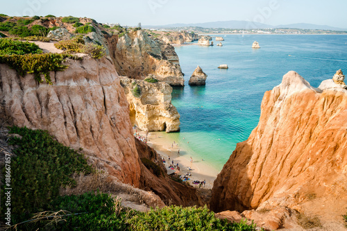 Camilo Beach in Lagos, Algarve, Portugal. A tiny secret beach between the limestone walls. 200 wooden steps down to sheltered, sandy cove divided by ochre-colored rocks with hand-dug tunnel.