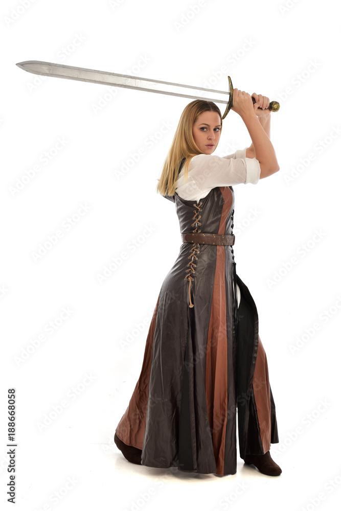 full length portrait of girl wearing brown fantasy costume, holding a sword. standing pose on white studio background. full length portrait of girl wearing brown fantasy costume, holding a sword. standing pose on white studio background.