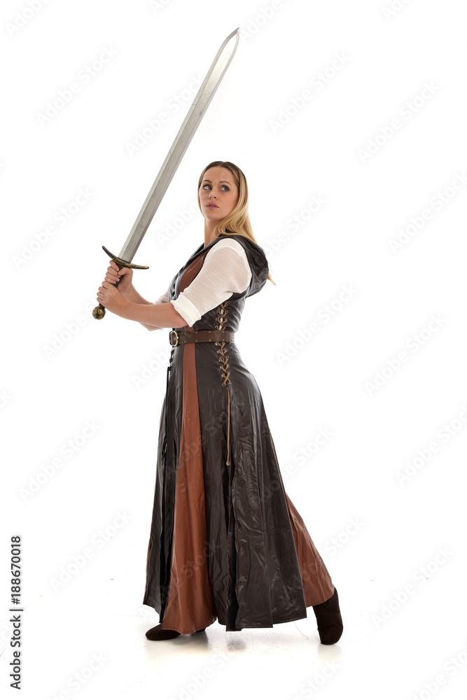 full length portrait of girl wearing brown fantasy costume, holding a sword. standing pose on white studio background. full length portrait of girl wearing brown fantasy costume, holding a sword. standing pose on white studio background.