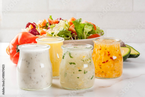 Set of classic salad dressings - honey mustard, ranch, vinaigrette, lemon & olive oil,  on white marble table, copy space