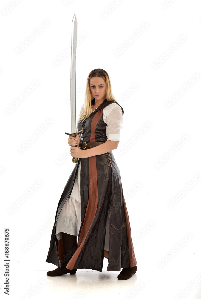 full length portrait of girl wearing brown fantasy costume, holding a sword. standing pose on white studio background. full length portrait of girl wearing brown fantasy costume, holding a sword. standing pose on white studio background.