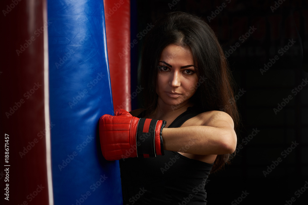 Portrait of woman kicking boxing bag
