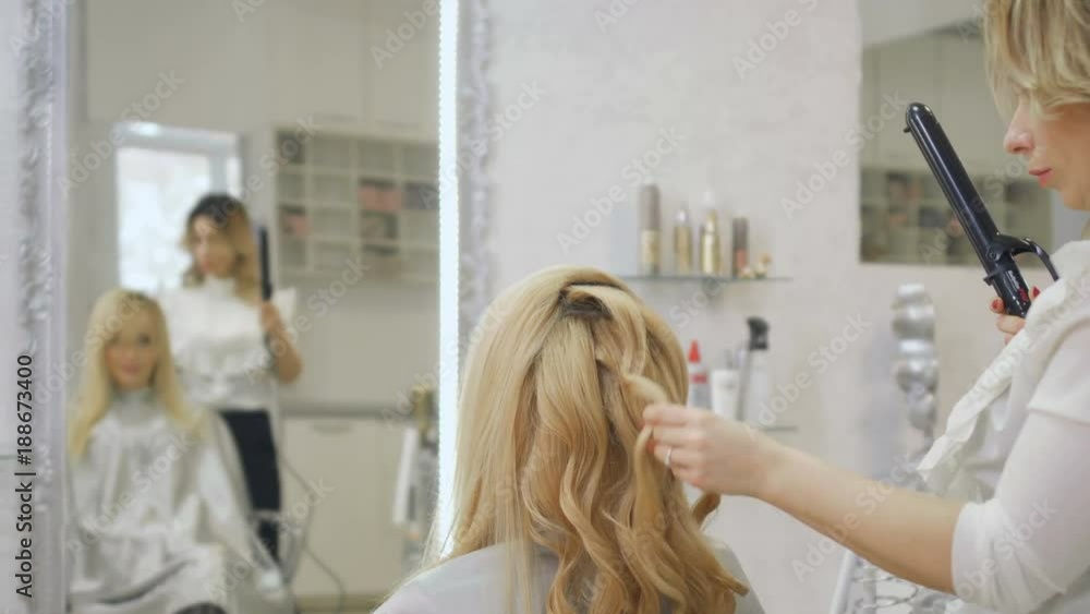 Hairdresser curls blonde hair with curling iron Hairdresser curls blonde hair with curling iron