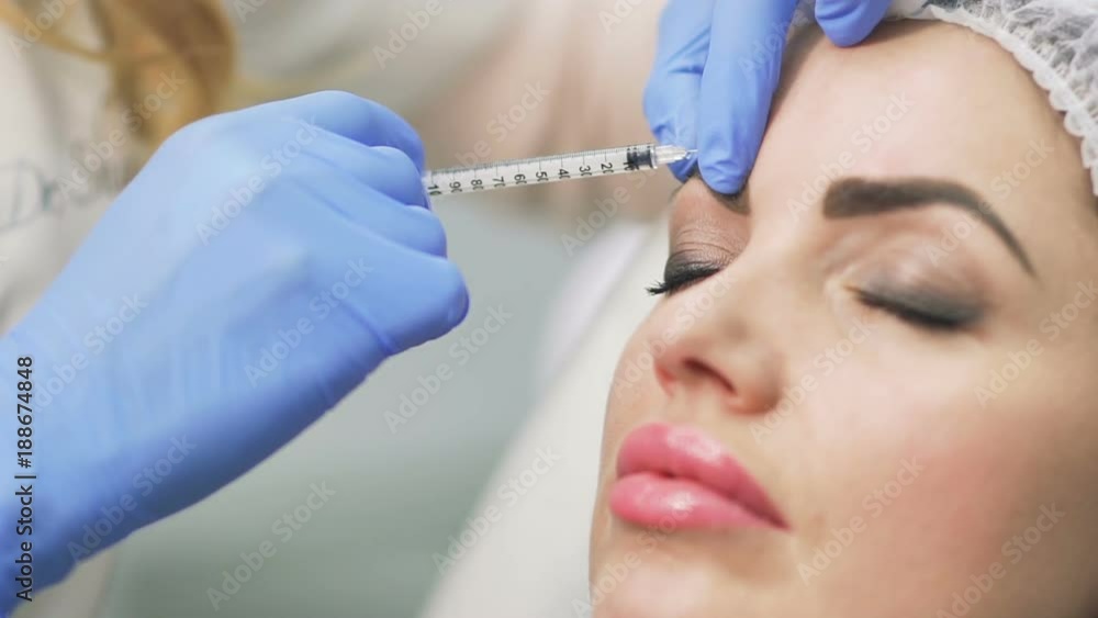 Beautician makes botox injection in the forehead Beautician makes botox injection in the forehead