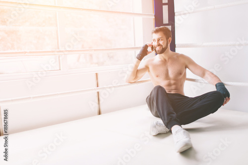 Handsome bearded boxer with bare torso is practicing at the fight club
