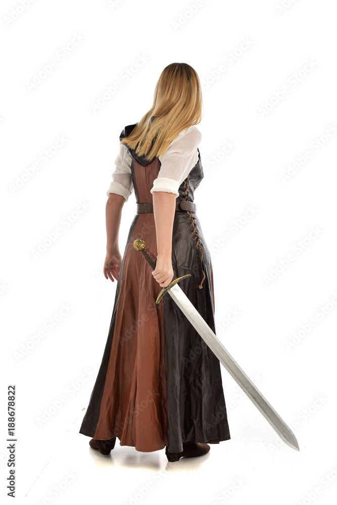 full length portrait of girl wearing brown fantasy costume, holding a sword. standing pose on white studio background. full length portrait of girl wearing brown fantasy costume, holding a sword. standing pose on white studio background.