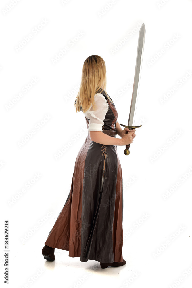 full length portrait of girl wearing brown fantasy costume, holding a sword. standing pose on white studio background. full length portrait of girl wearing brown fantasy costume, holding a sword. standing pose on white studio background.