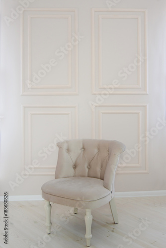 minimalism interior design. old and refined soft chair standing near the dairy wall in an empty white living room