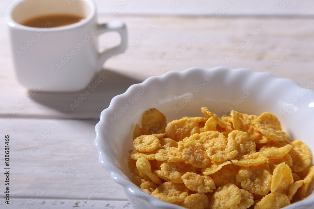 Corn Flakes cereal in a bowl, glass with milk and cap with espresso coffee. Morning breakfast. Corn Flakes cereal in a bowl, glass with milk and cap with espresso coffee. Morning breakfast.