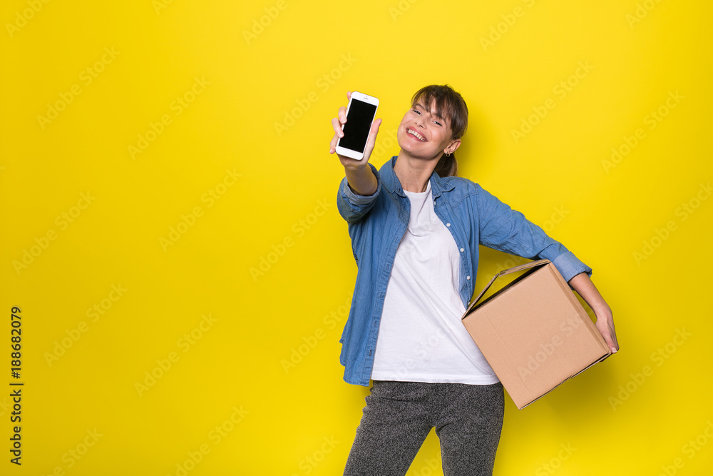 isolated woman on yellow with cardboard box - obrazy, fototapety, plakaty 