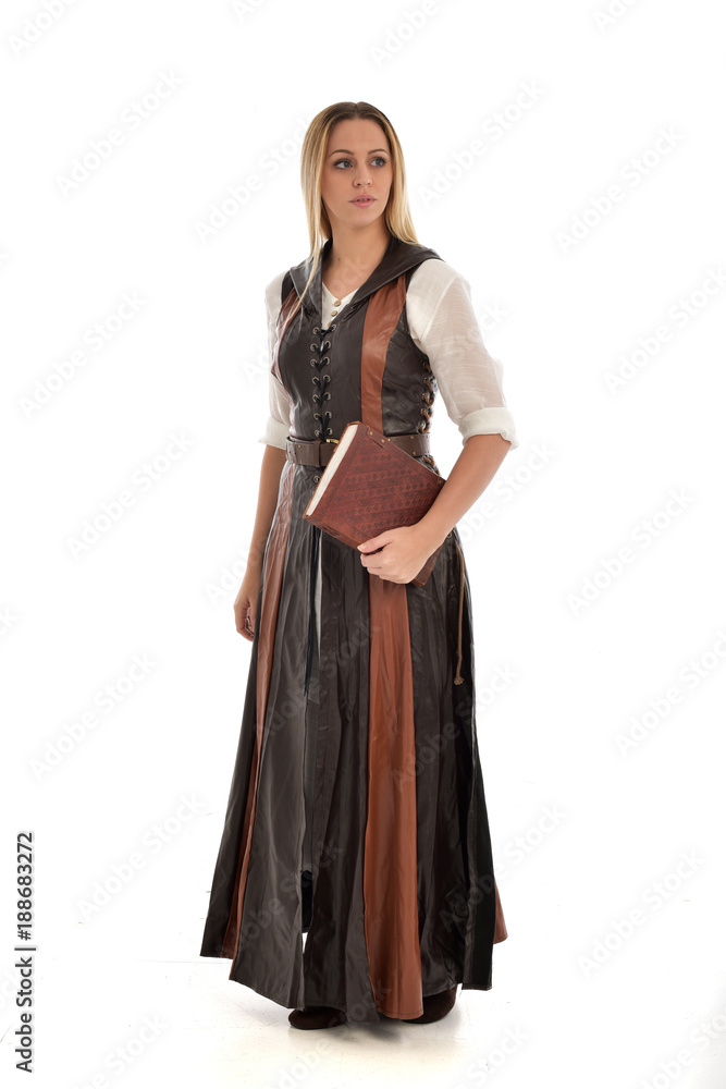  full length portrait of girl wearing brown  fantasy costume, holding a book. standing pose on white studio background. 