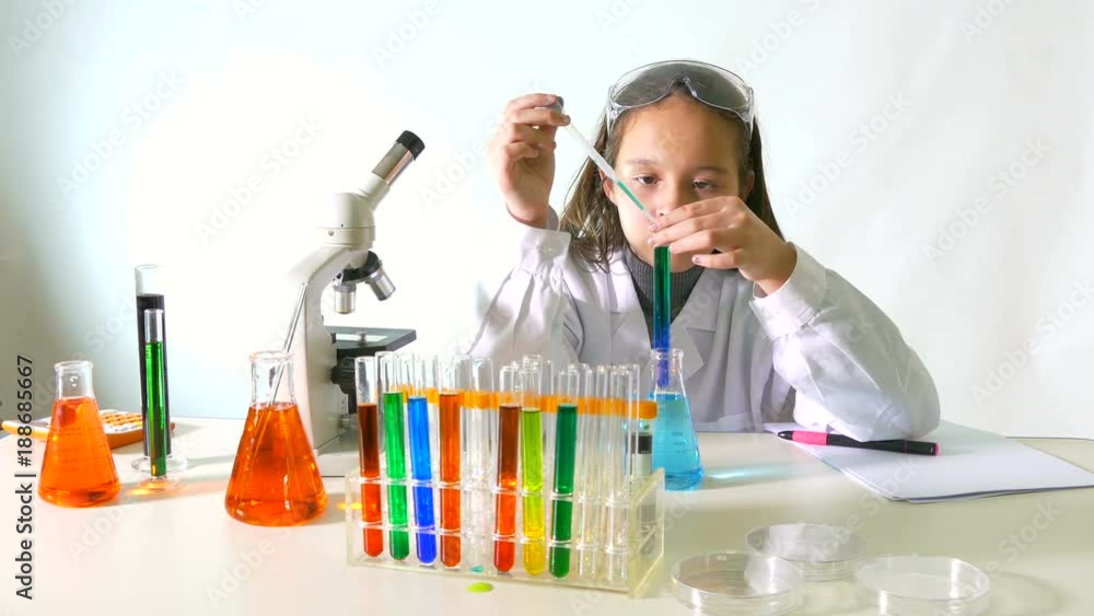 Young girl doing science experiment, transfers liquids with pipette Young girl doing science experiment, transfers liquids with pipette