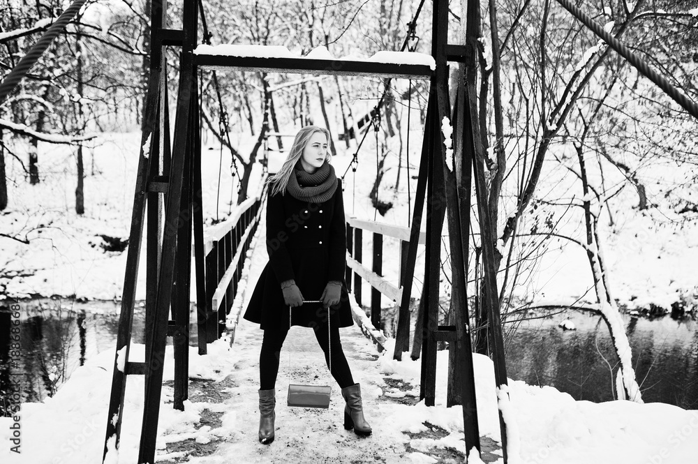 Blonde girl in red scarf and coat walking on bridge at park on winter day. Blonde girl in red scarf and coat walking on bridge at park on winter day.