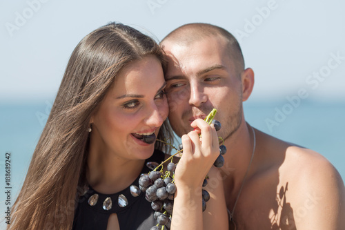 Guy and girl eating black grapes looking each at other