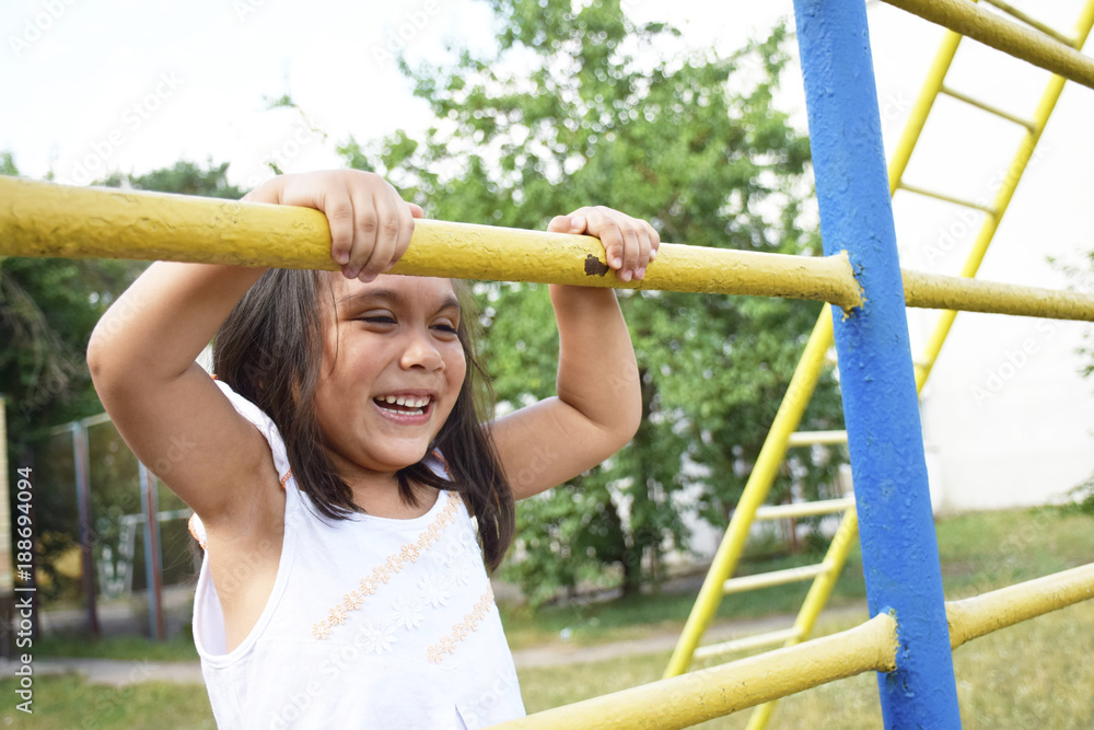 Fototapeta premium Playful latin little girl climbing on the playground. 