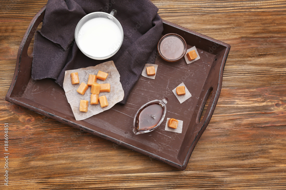 Composition with tasty candies and caramel sauce on table Composition with tasty candies and caramel sauce on table