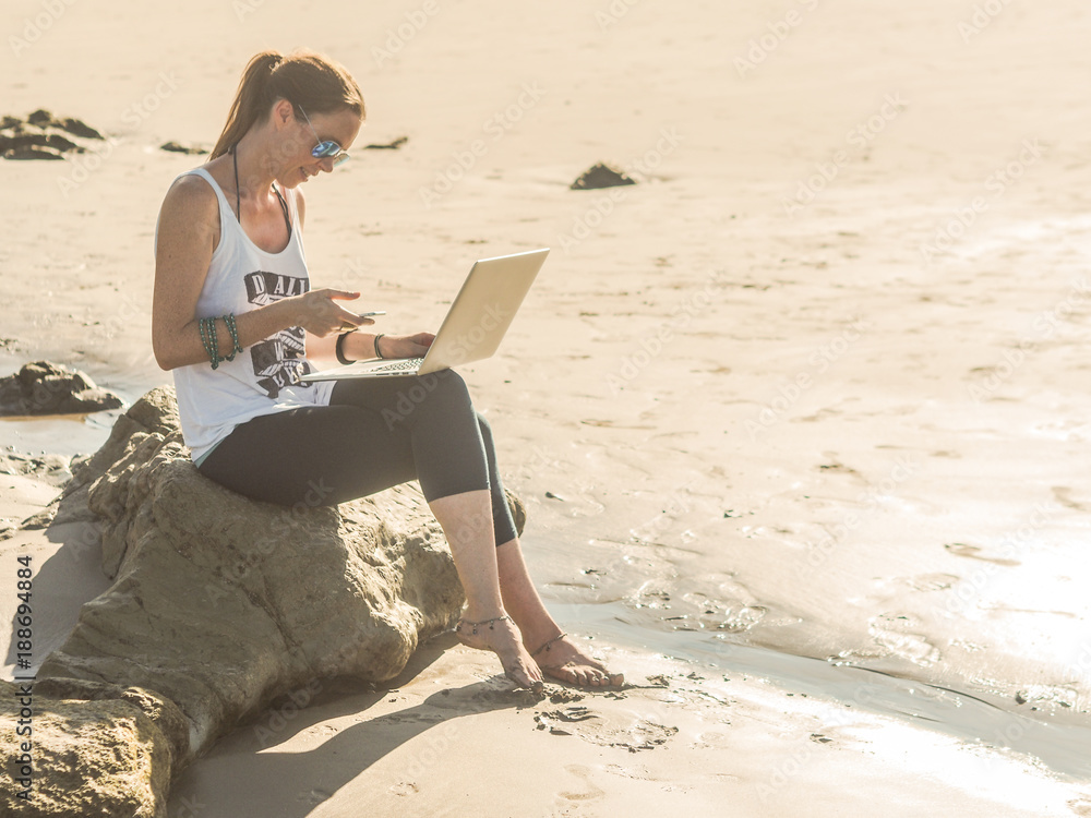 digital nomad working on the beach with laptop and mobile
