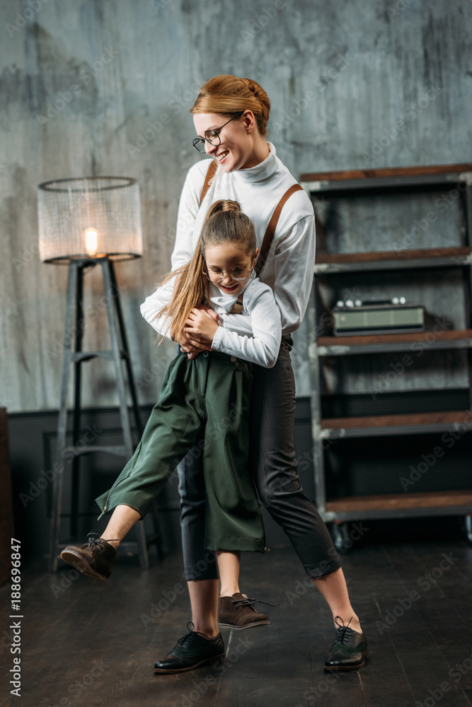 Naklejka premium happy young mother and daughter playing in loft apartments