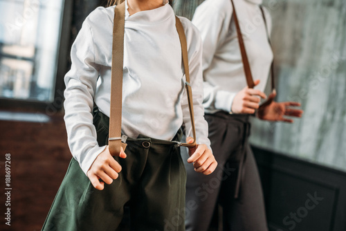 cropped shot of mother and daughter in stylish clothing with suspenders