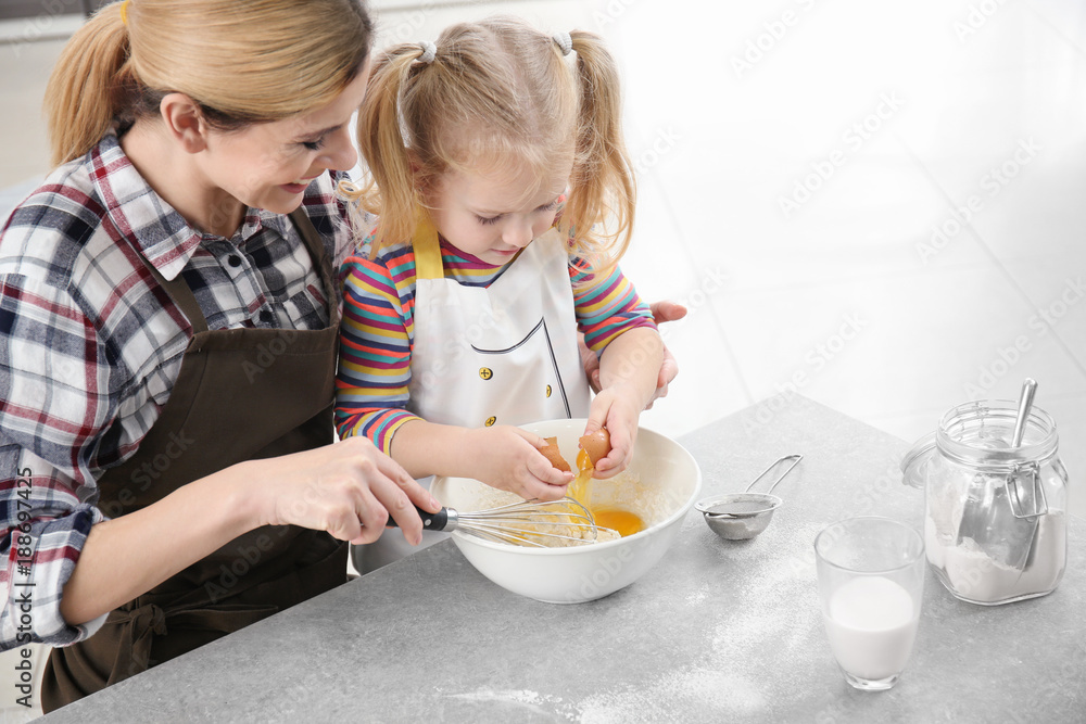 Mother and daughter preparing dough indoors Mother and daughter preparing dough indoors