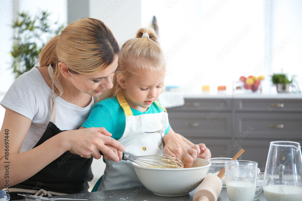 Mother and daughter preparing dough indoors Mother and daughter preparing dough indoors