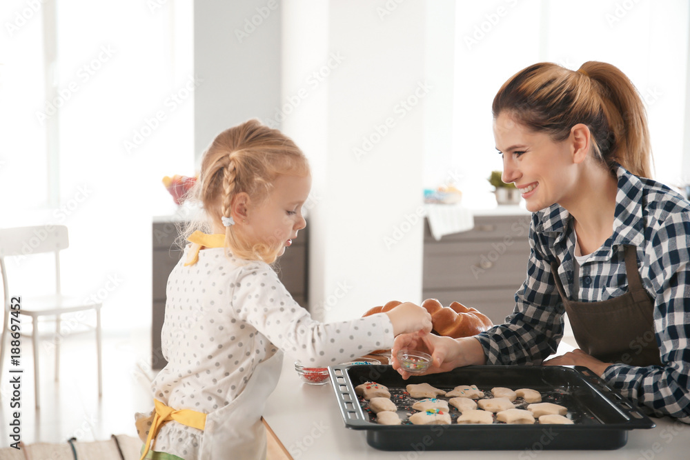 Mother and daughter decorating cookie dough with sprinkles indoors Mother and daughter decorating cookie dough with sprinkles indoors