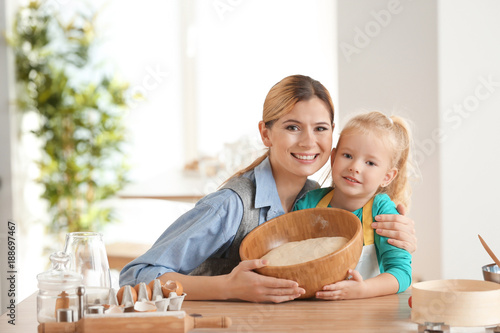 Mother and daughter preparing dough indoors