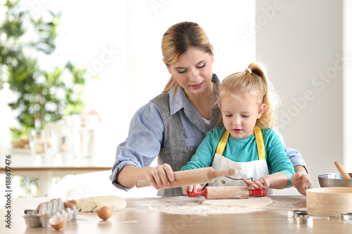 Mother and daughter with dough at table indoors