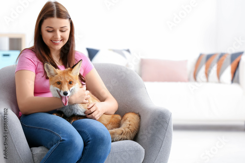 Young woman with pet fox indoors
