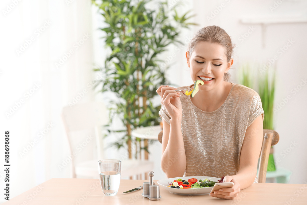 Young beautiful woman eating fresh salad at home