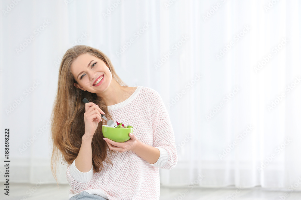 Young beautiful woman eating fresh salad on light background Young beautiful woman eating fresh salad on light background