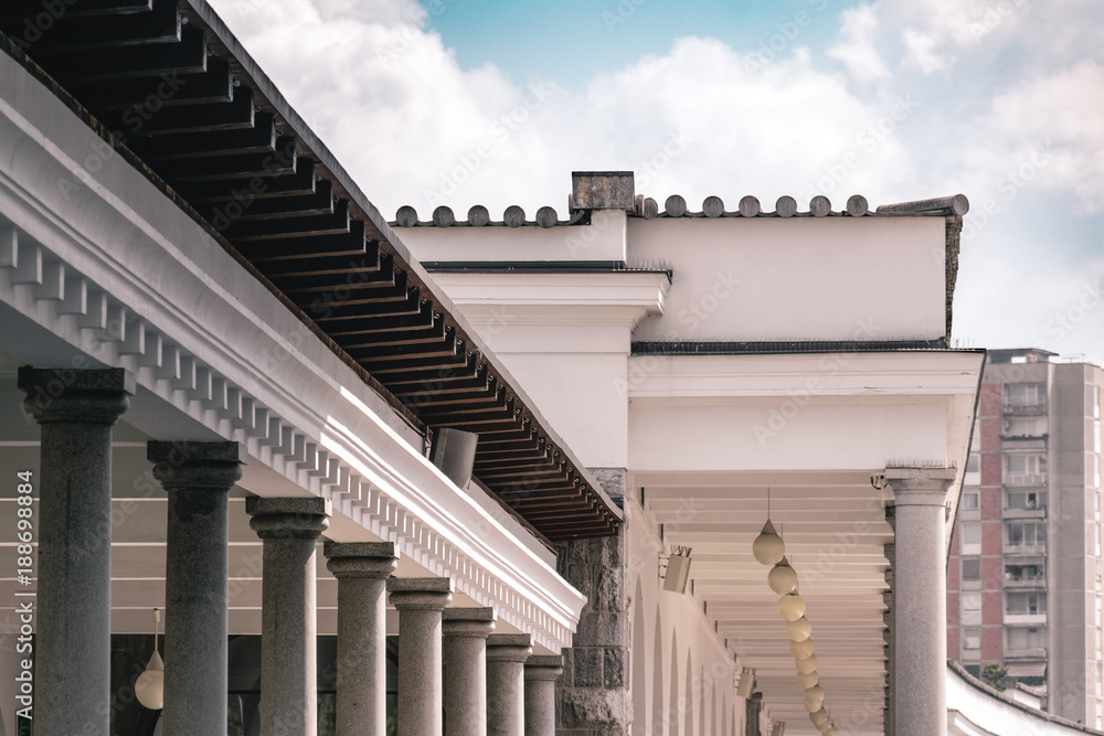 Fotografie Colonnade structure with modern building in the background