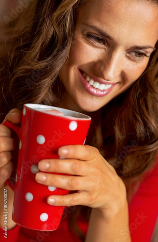 Happy young woman in christmas red dress having cup of hot bever